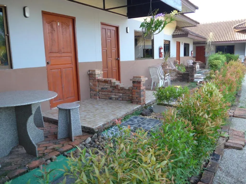 Walkway along Forum House Hotel bungalow-style building with wooden doors and lush gardens
